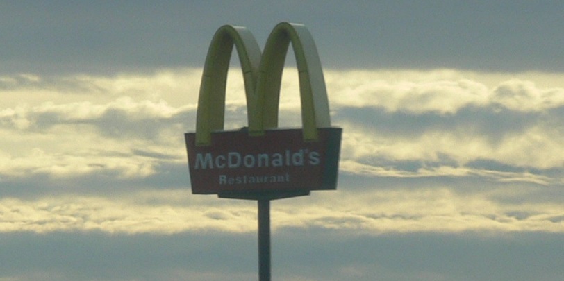 McDonald's Restaurant sign against sky and clouds.