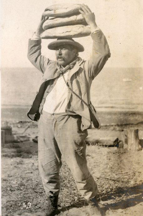 Image is part of a series called Santa Cruz Island Winery, this image shows a man balancing 3 loaves of bread on his head