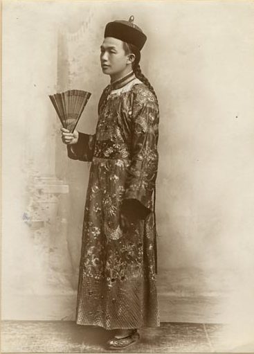 Lee Tung Foo photo in traditional robe and brimless cap, holding a fan