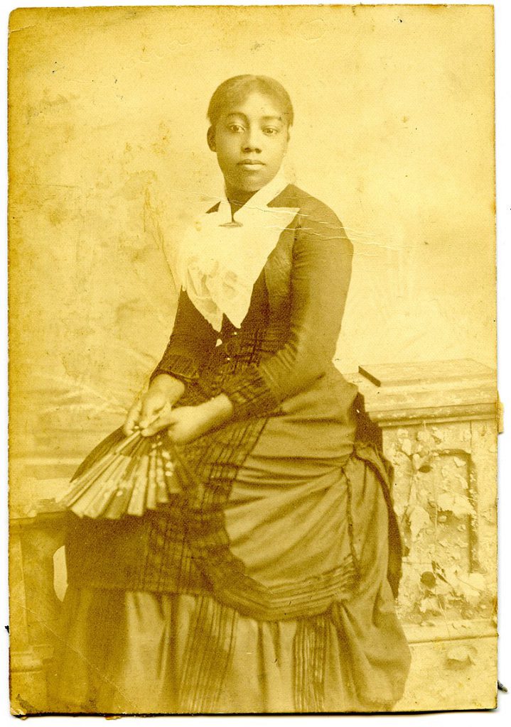 photo of a young Lydia Flood Jackson sitting, dessed in long black dress with white collar