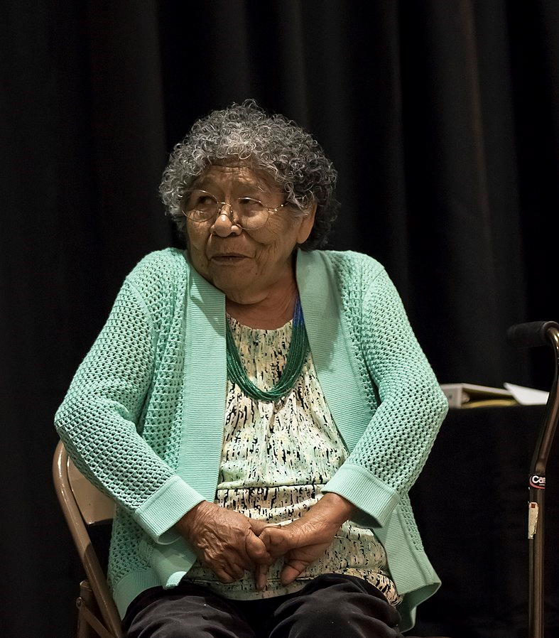 Shows Marie Wilcox seated and on the verge of a smile