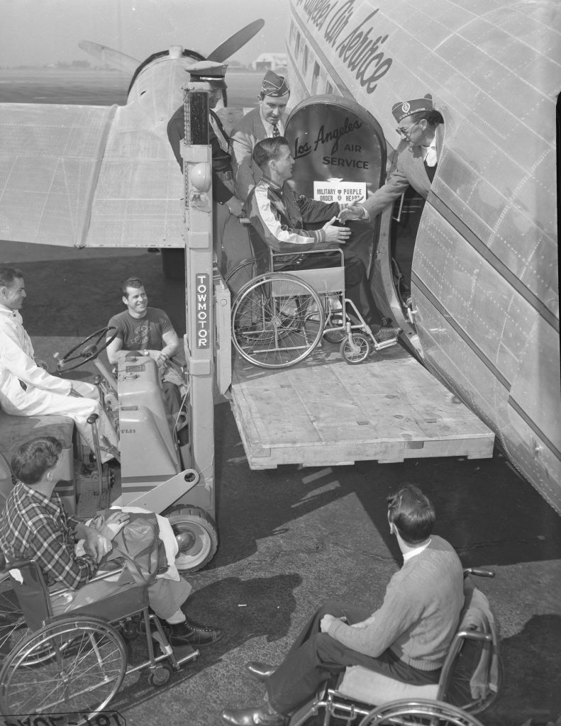 ALL ABOARD! -- Jack Heller, member of the wheel-chair basketball team from Birmingham General Hospital, is hoisted aboard Los Angeles Air Service plane at Burbank as teammates wait turn.