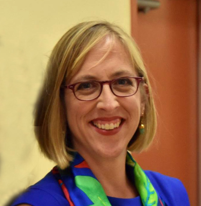 A blonde woman in glasses smiling at the camera.